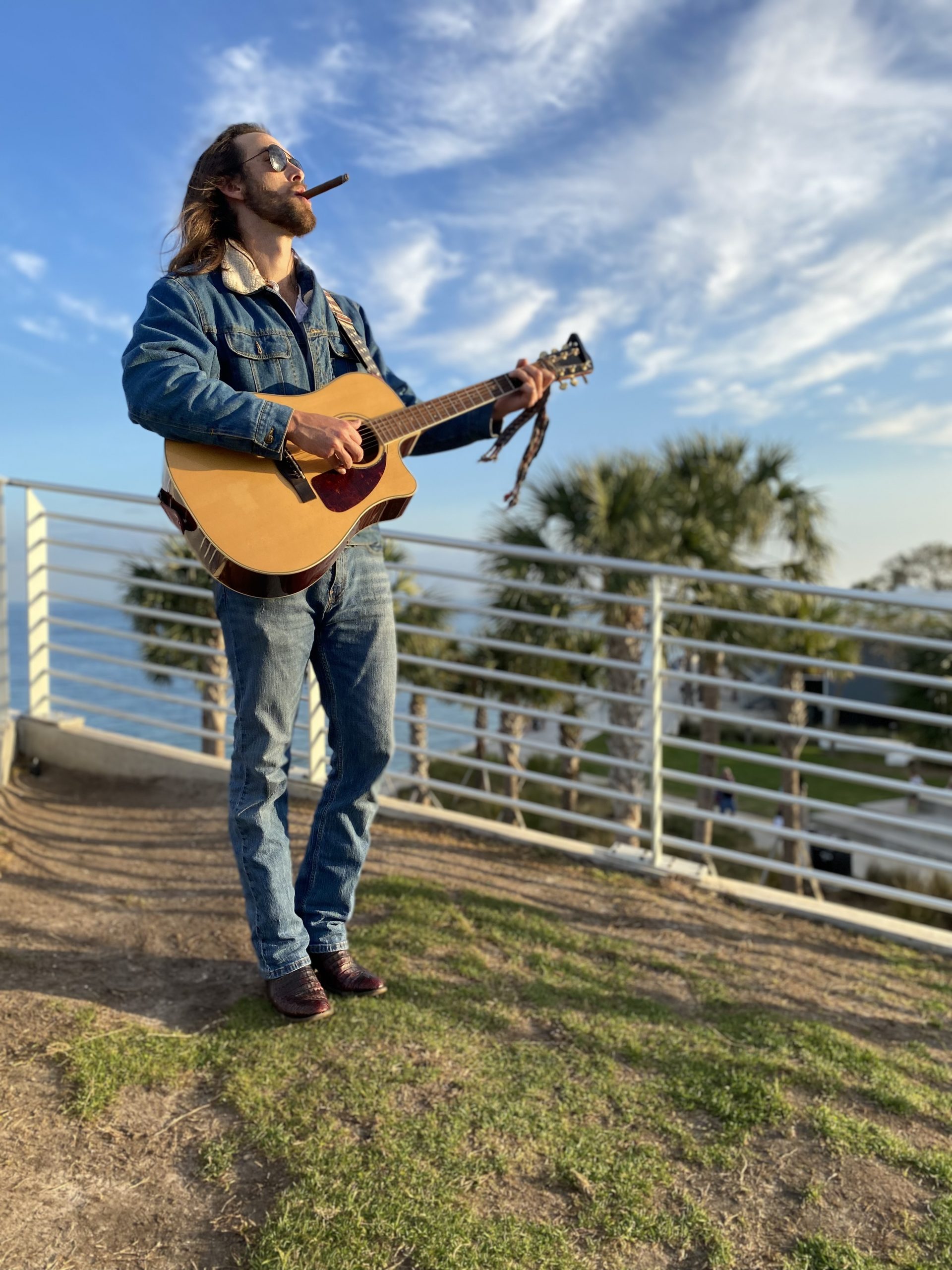 Mark Marra with guitar outdoors by the waterfront